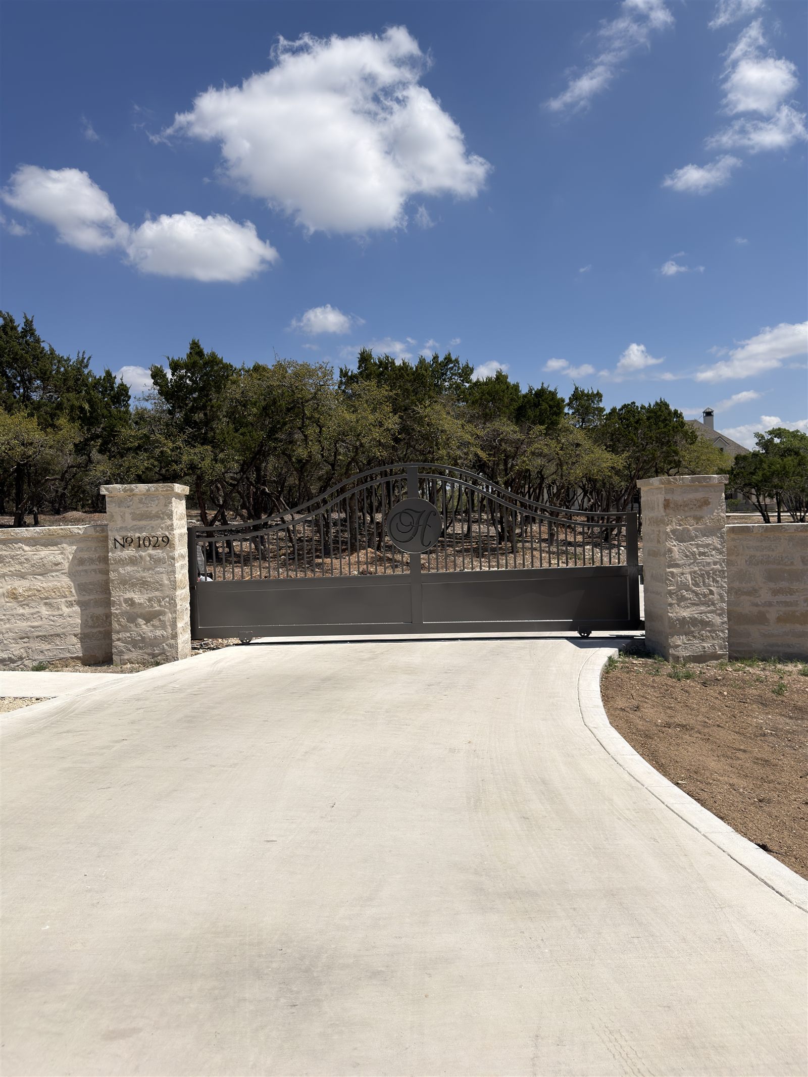 Custom ornate metal art gate with stone masonry columns
